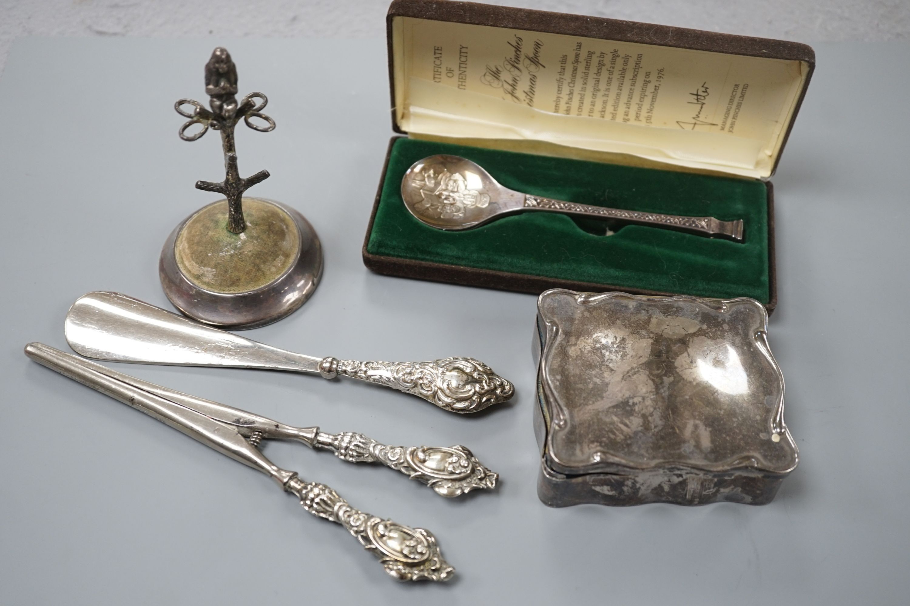 A George V silver mounted hat pin stand, two silver spoons, a silver mounted trinket box, a pair of glove stretchers and a shoe horn.